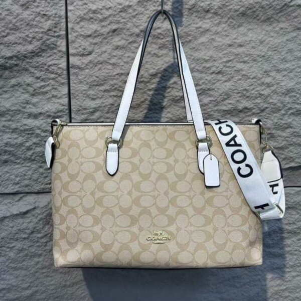 Cartera COACH tote color beige con asas blancas y logo dorado.
